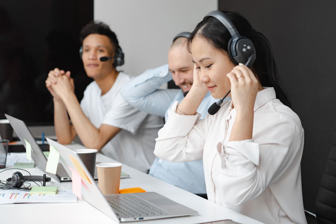 Customer support team wearing headsets working at computers in a help desk